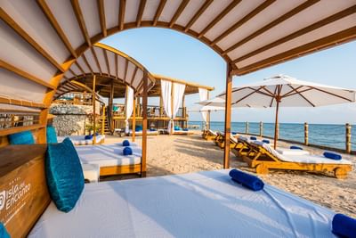 Sunbeds under cabanas arranged outdoors on seashore by the sea at Hotel Isla Del Encanto
