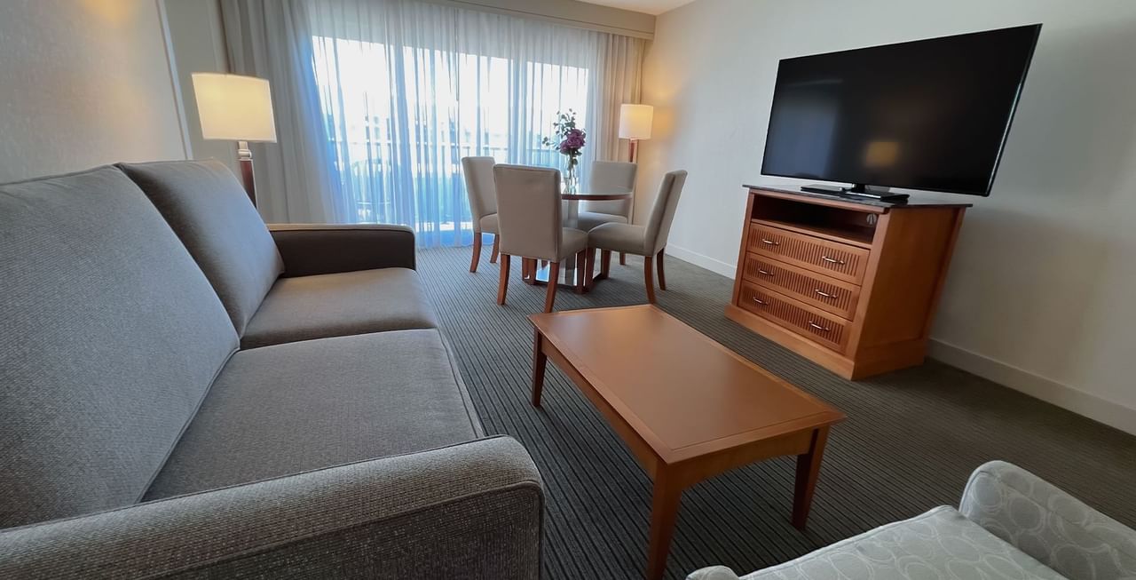 Hotel suite with couch, coffee table, chairs, and TV