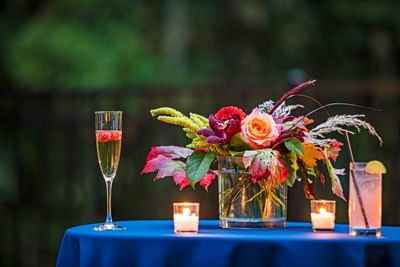 Floral bouquet centerpiece with candles and drinks on the table linen at Sable Oaks Weddings and Events