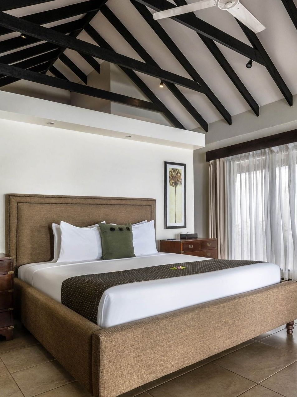 White bedding with two dark wood dressers and grey armchair in Shefa Pool Villa at warwick le lagon-vanuatu