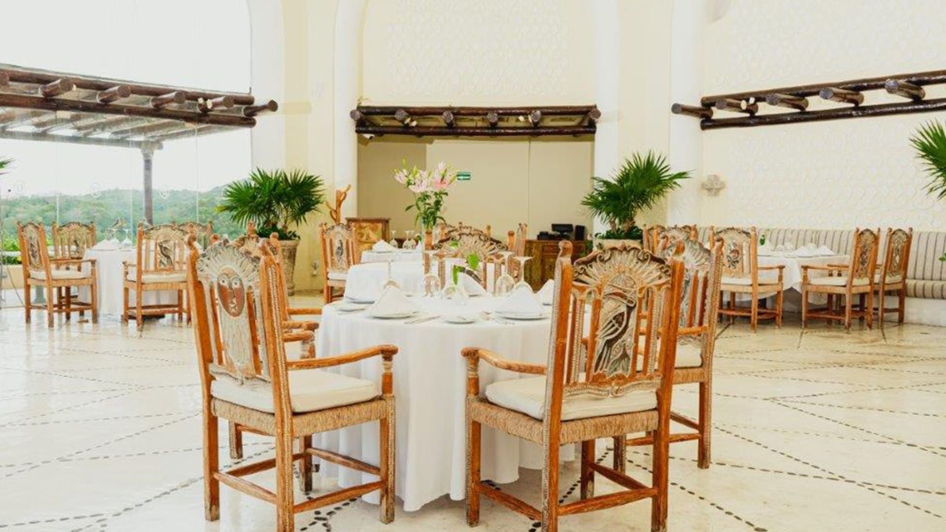 Tierra Mia restaurant featuring sun-carved chairs by a round table with plates at Quinta Real Huatulco