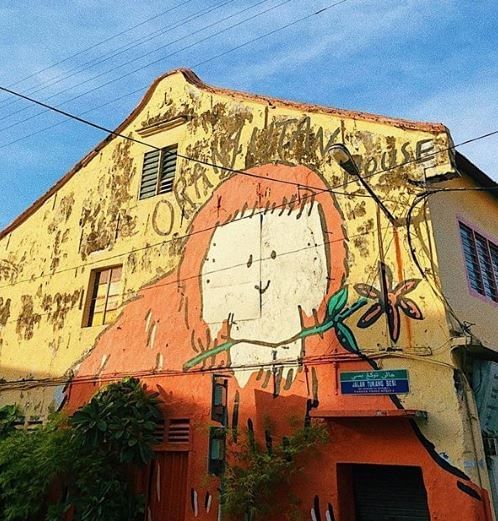 Colorful mural of a playful orange character on The Orangutan House, surrounded by greenery near YTL Hotels