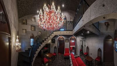Dracula's Fangs with a grand chandelier, stone walls, red seating, and a spiral staircase at The Roxbury