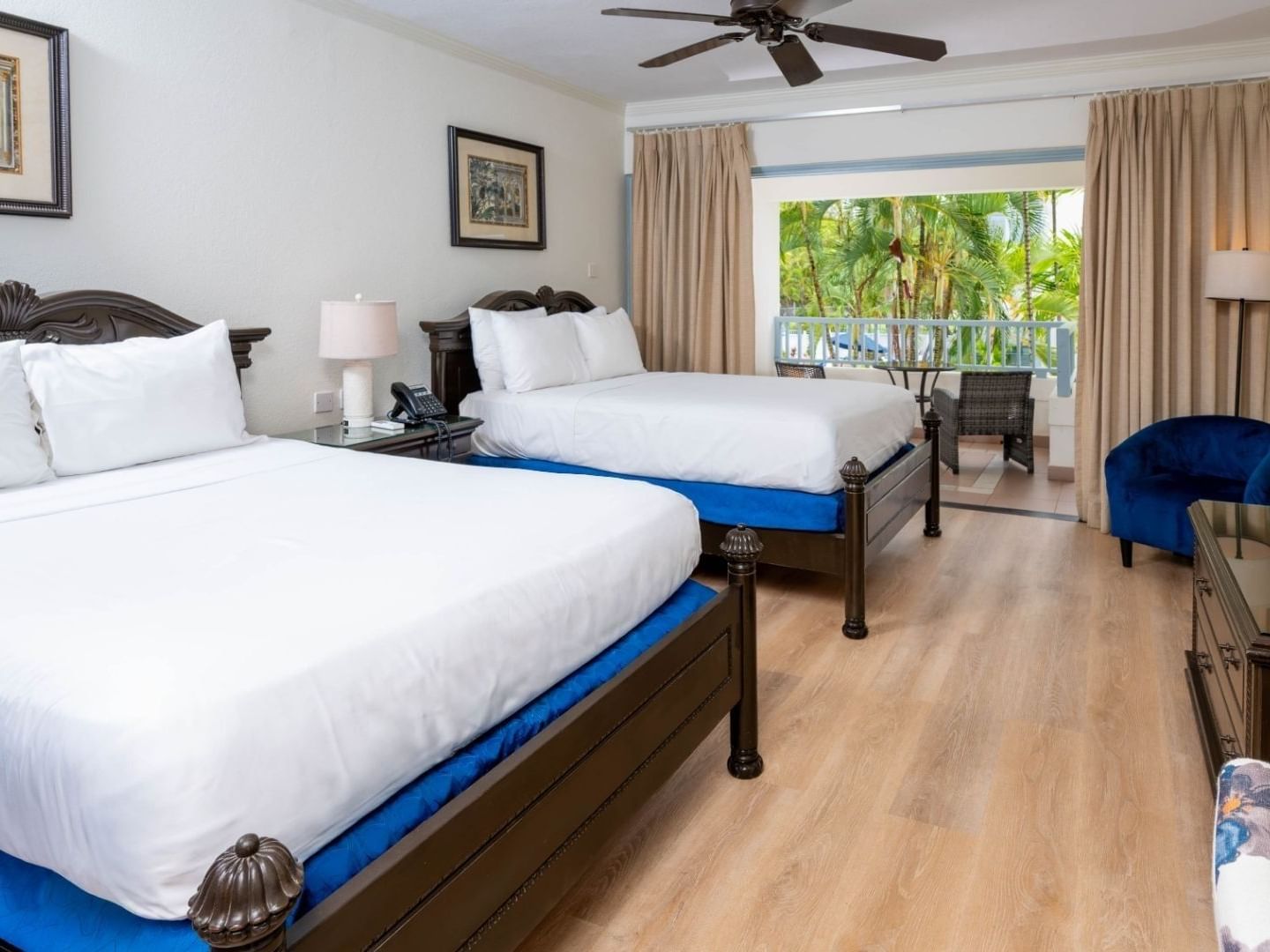 Two beds with white linens and blue bed skirts in a hotel room at Savannah Beach Hotel.
