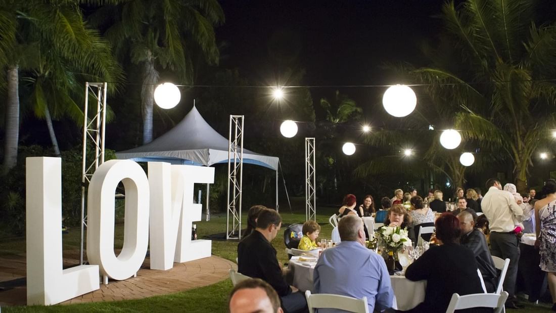 Outdoor evening receptions with large LOVE letters and guests dining under glowing lanterns at Mercure Hotel Townsville