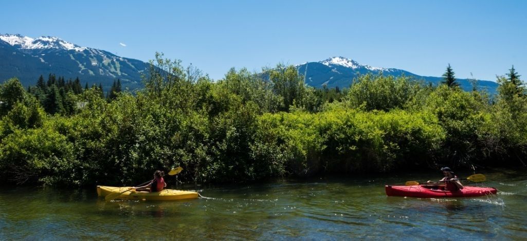 Kayakers paddling the River of Golden Dreams with Whistler mountain views.