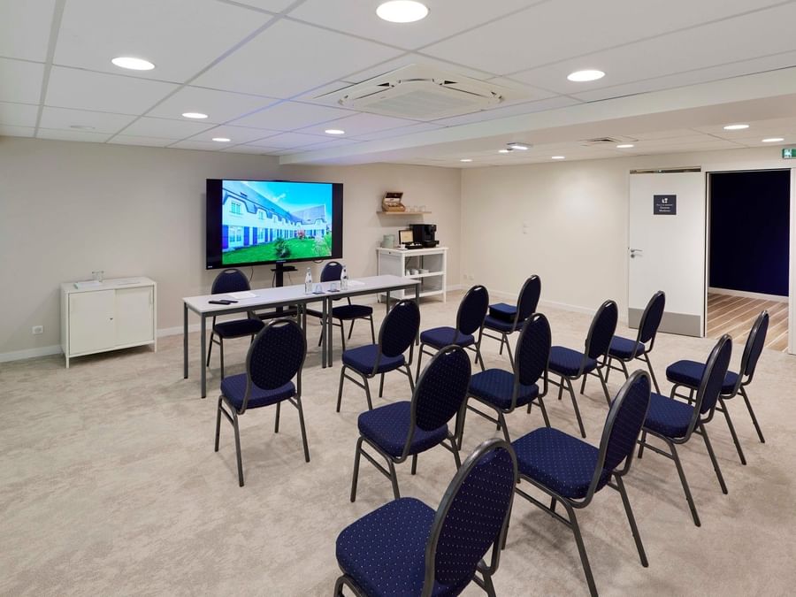 Salle de réunion moderne avec chaises bleues et écran à Hôtel La Marébaudière.
