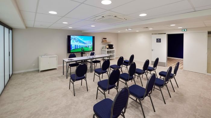 Salle de réunion moderne avec chaises bleues et écran à Hôtel La Marébaudière.