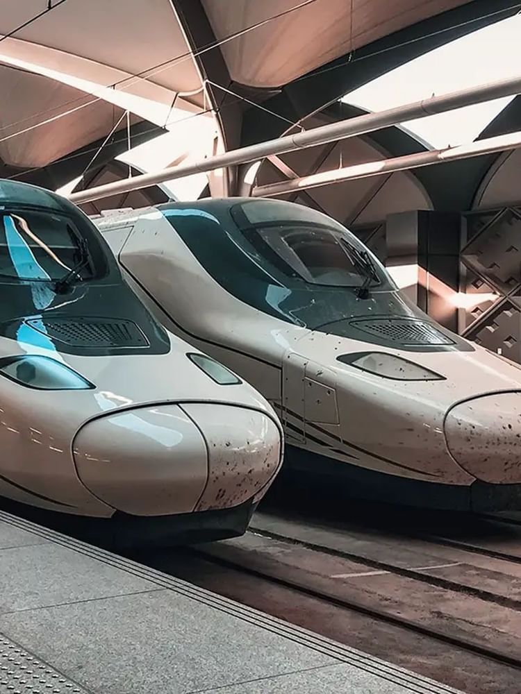 Two modern high-speed trains parked at the Madinah station platform under a sleek roof at Saja Warwick Madinah