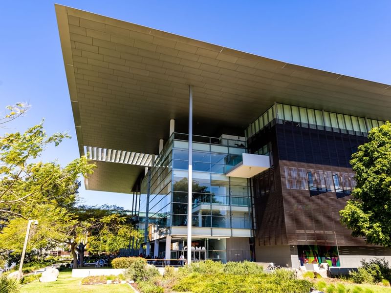 Exterior of QAGOMA with glass facade and lawn area near Sofitel Brisbane Central