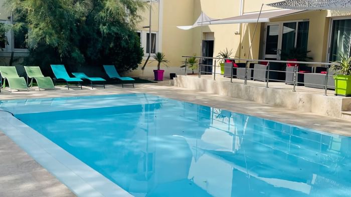 Outdoor pool with sun loungers at The Originals Hotels