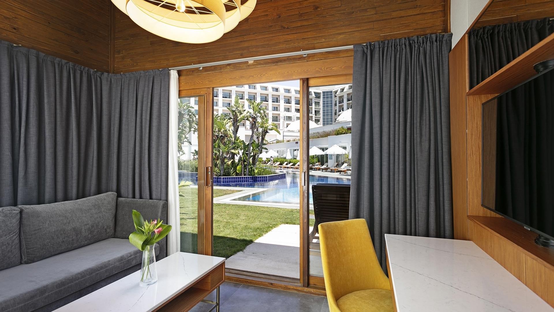 Titanic Deluxe Golf Belek’te Bali House Swim-up’da TV oturma alanının yanında çalışma masası.