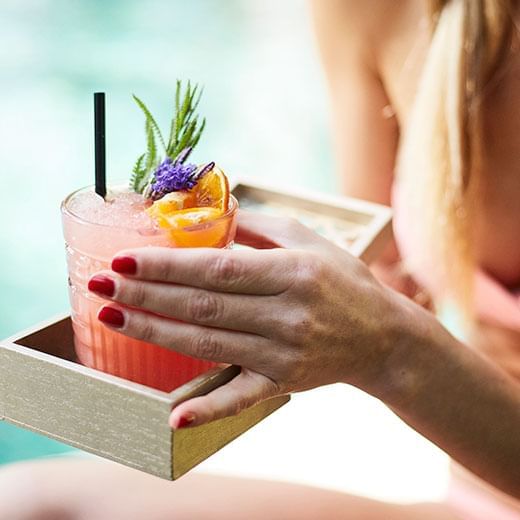 Closeup of a lady having a cocktail by a pool at Marbella Club