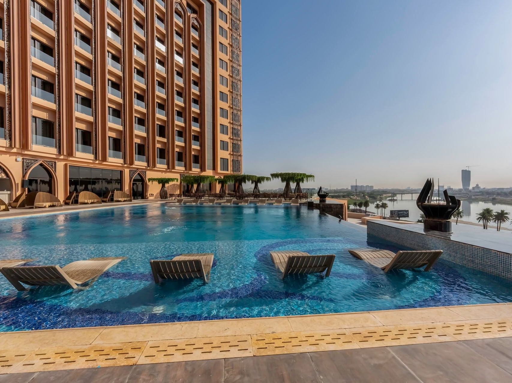 Large pool with lounge chairs in front of World Heart Hotel Baghdad.