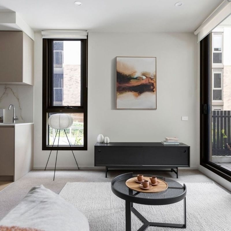 Modern apartment living room with a dining area, sliding glass doors, and a small kitchen.