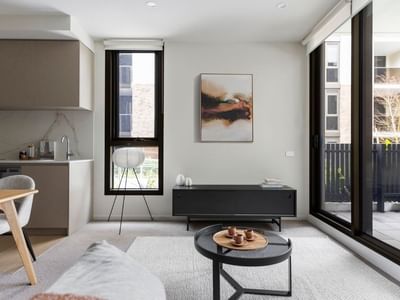 Modern apartment living room with a dining area, sliding glass doors, and a small kitchen.