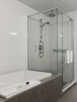 Salle de bain avec douche et lavabo dans la suite Junior du Warwick Le Crystal