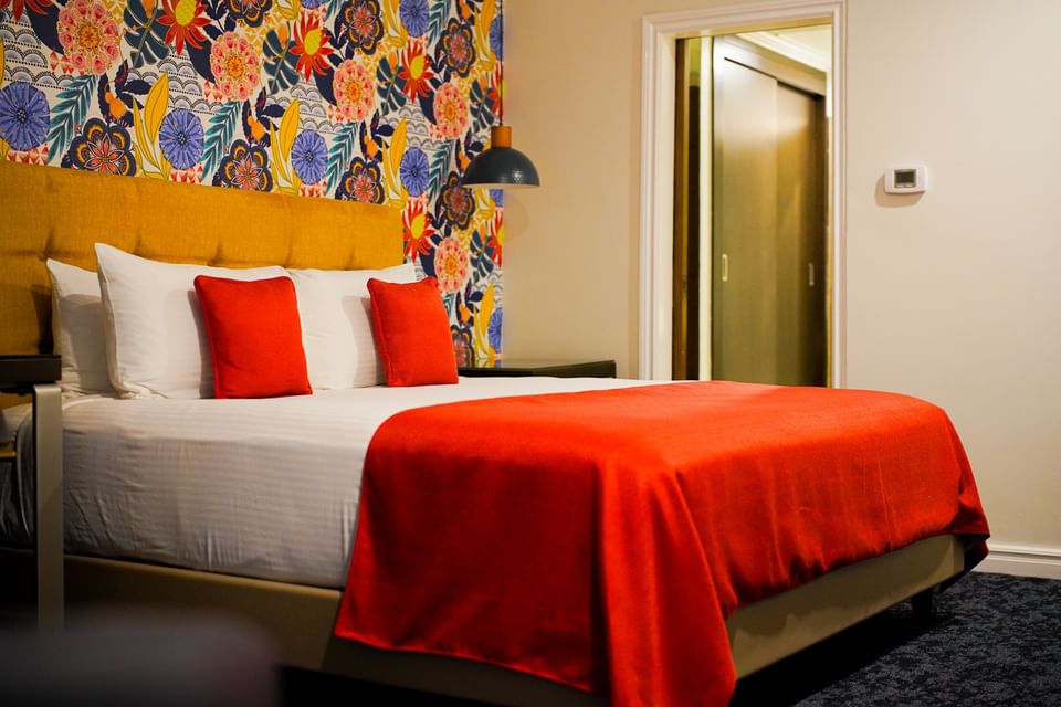 Plush king bed with pillows behind colorful wallpaper in Royal Two Bedroom Suites at Jamaica Pegasus Hotel