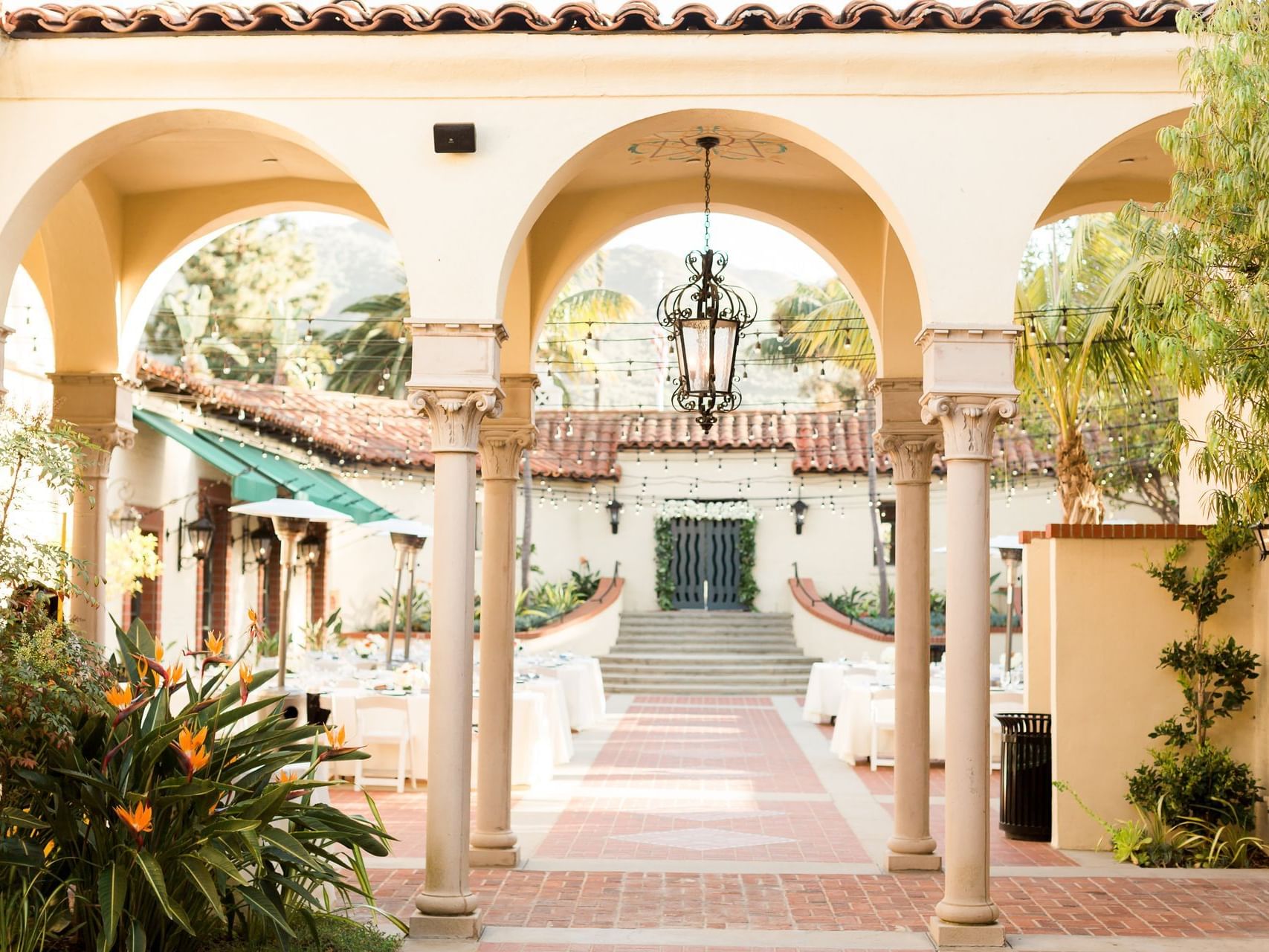 Elegant outdoor corridor with arches, chandelier, and set dining tables at Catalina Island Company