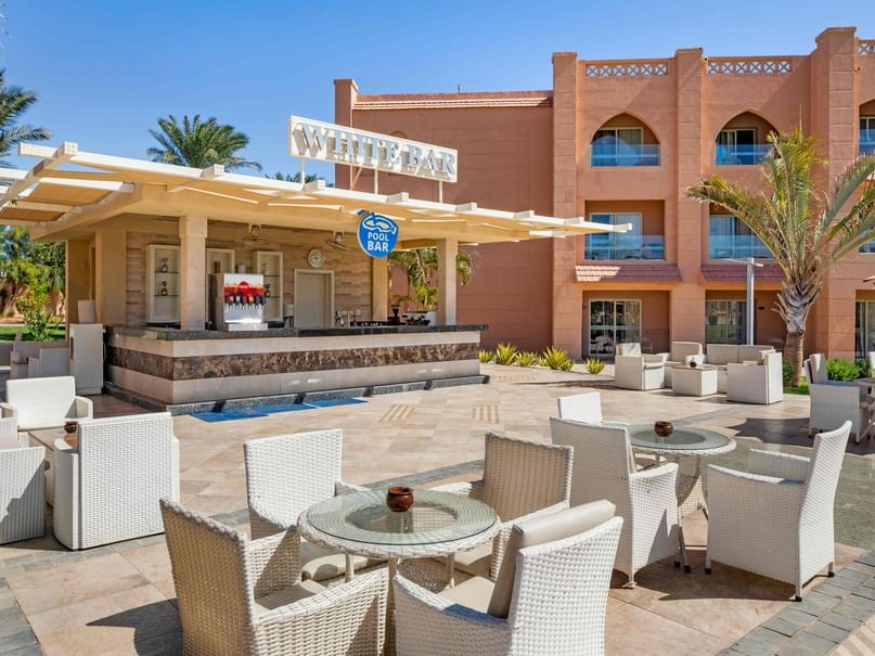 Outdoor seating area with white chairs and tables in front of a building labeled White Bar.
