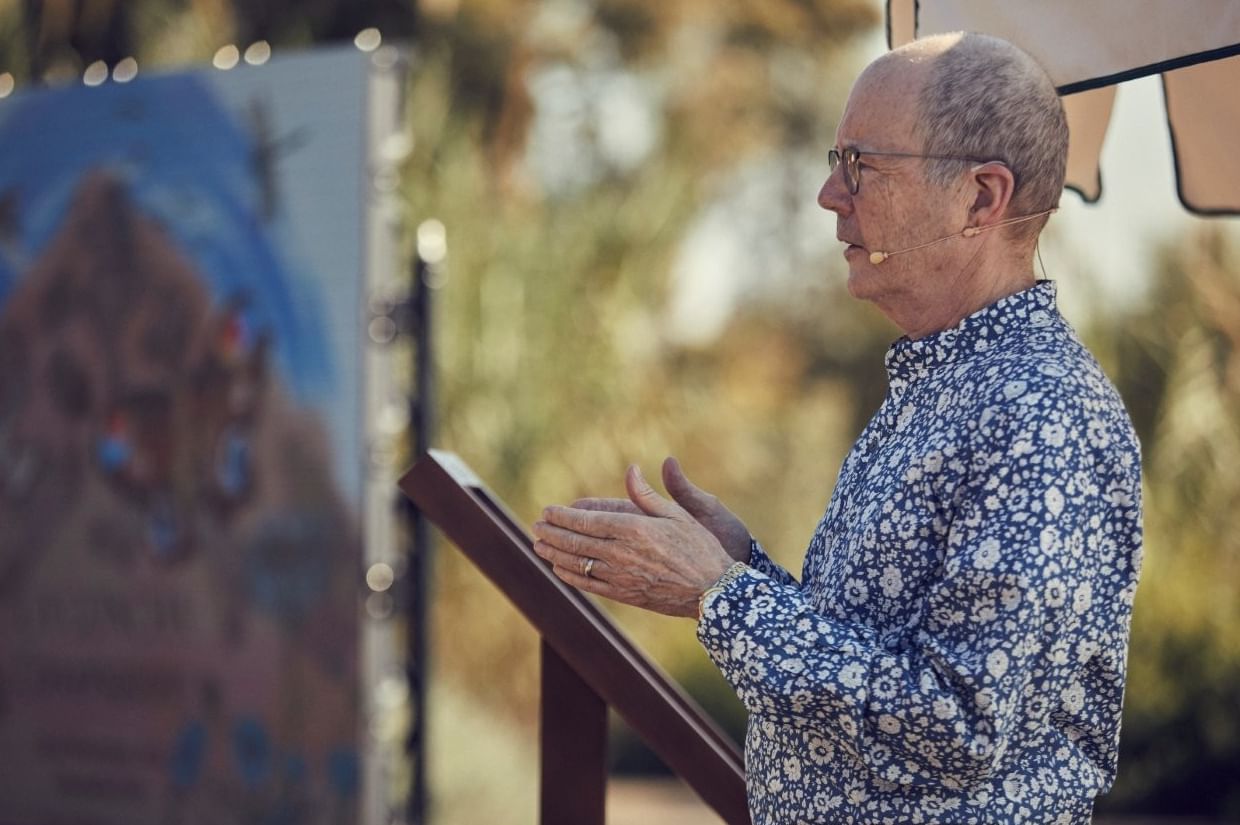 Man in a blue floral shirt speaking at La Concha Conversations with an illustrated backdrop , Marbella Club