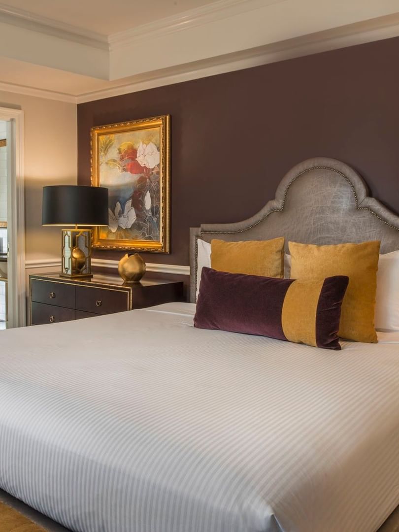King bed with purple accent wall, and a view into a marble bathroom in Follie Suite at Warwick New York