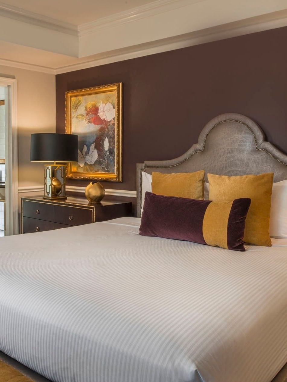 King bed with purple accent wall, and a view into a marble bathroom in Follie Suite at Warwick New York