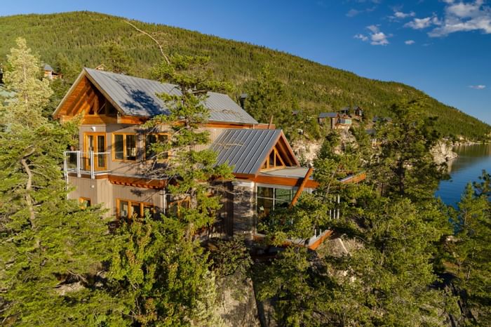 Aerial view of a house surrounded by trees, overlooking a lake and mountain.