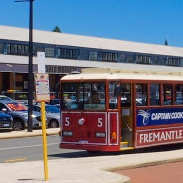 Red bus parked at a bus station near Be Fremantle