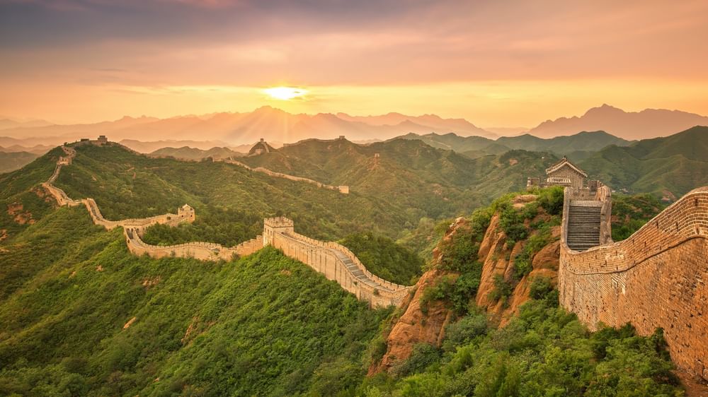 Beijing by mountain ridges under a golden sunset, surrounding lush green hills near warwick Hotels & Resort