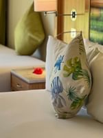 Tropical leaf pillow on a white bed by a wooden nightstand in Garden View Room at The Naviti Resort Korolevu, Fiji