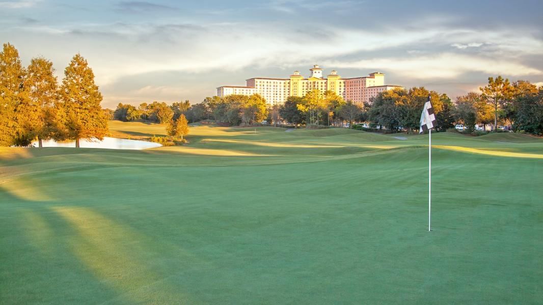 A large building is visible in the background of a golf course.