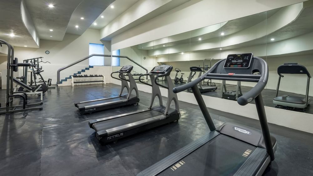 Gym facilities at Real Inn Nuevo Laredo, with rows of treadmills and mirrored walls for a complete workout
