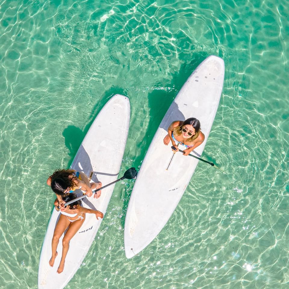 High angle view of ladies posing on paddleboards with clear waters at Paradise Beach Hotel