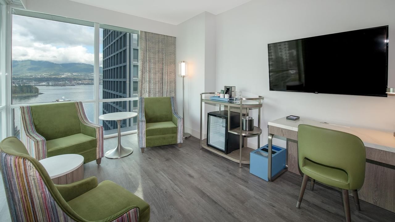 Hotel room with large window, furniture, and stunning views.