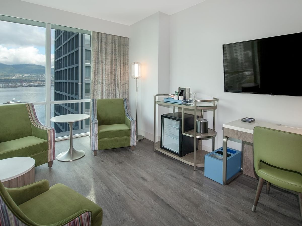 Spacious hotel room featuring large window, furniture, and views.