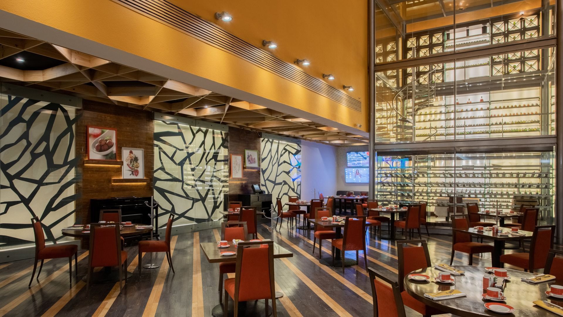 Modern dining room at Camino Real Monterrey, with red chairs and a glass-enclosed spiral staircase