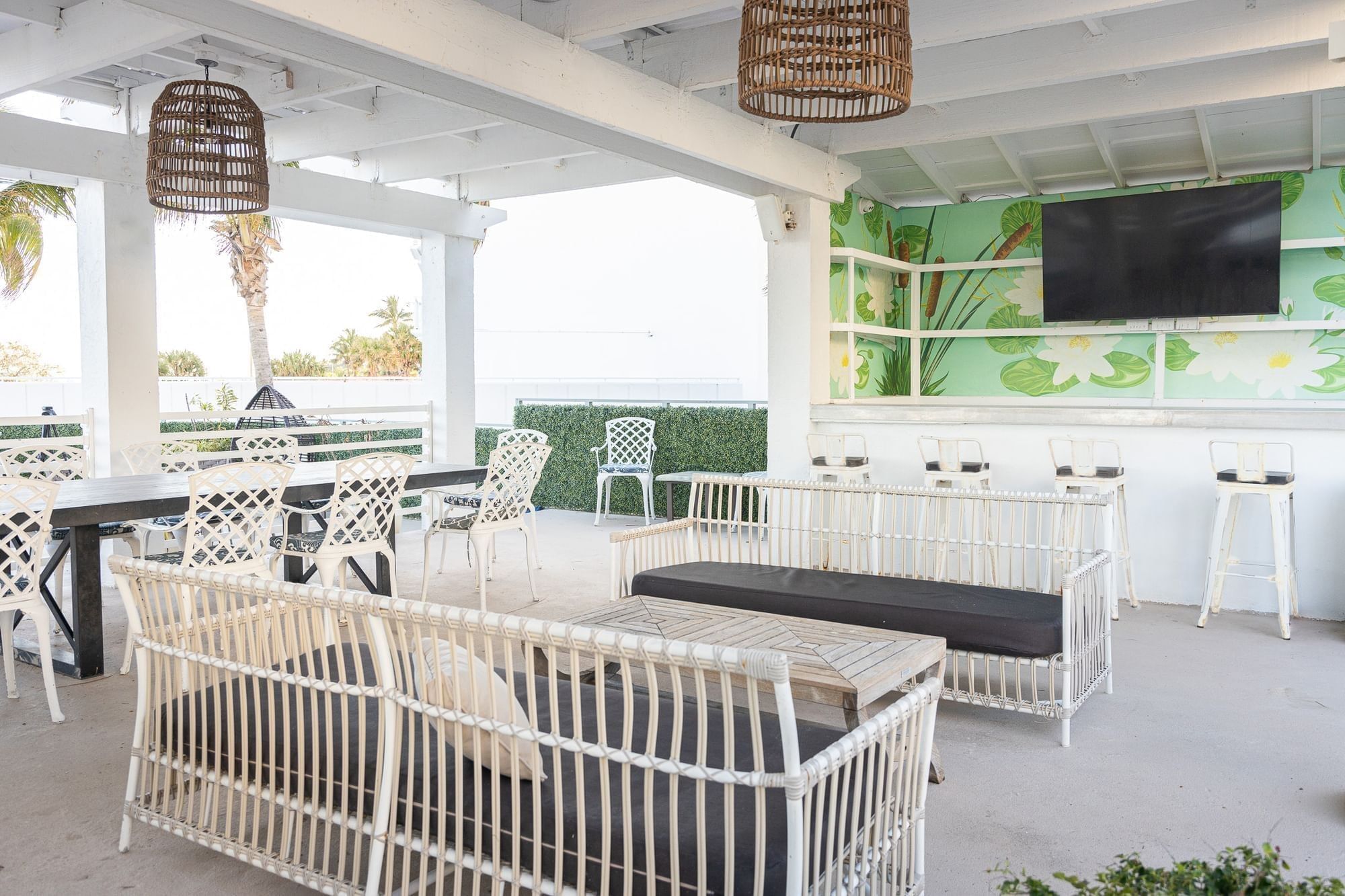 A white outdoor bar with a green wall and TV