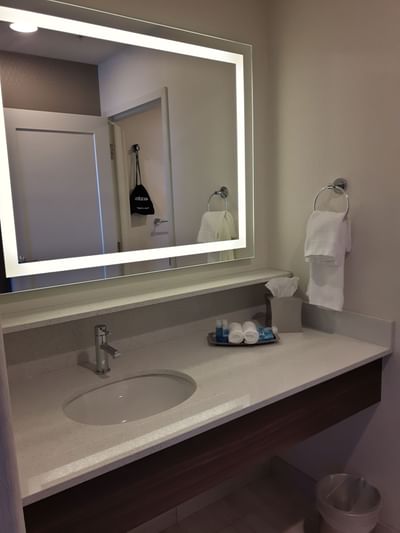 Vanity mirror and toiletries inside a washroom at Encore Suites Grande Prairie
