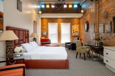 King bed, work desk with comfy chair & brick wall in King Premiere Urban Studio at Retro Suites Hotel