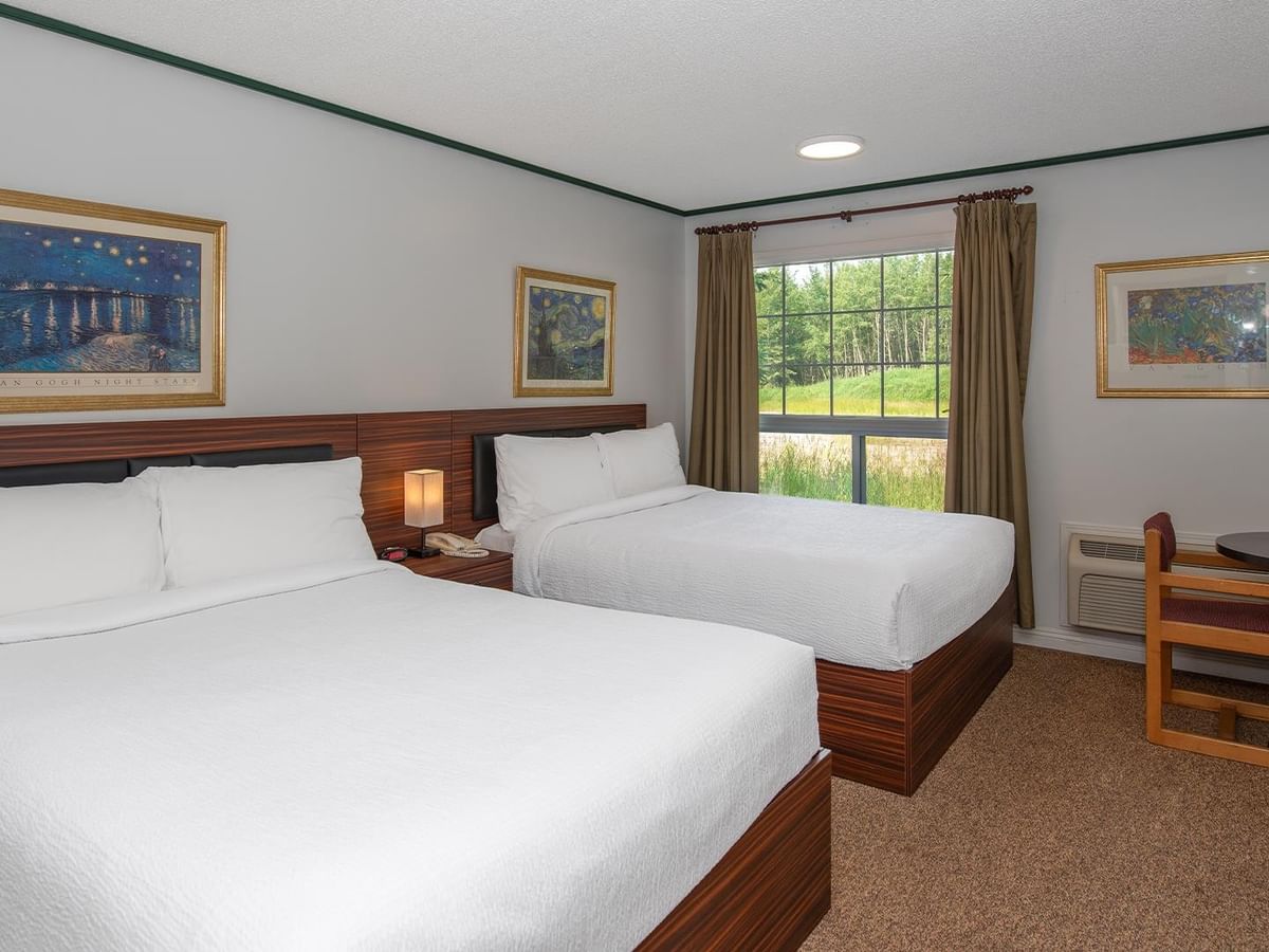 Guest room with two queen beds, a work desk and window