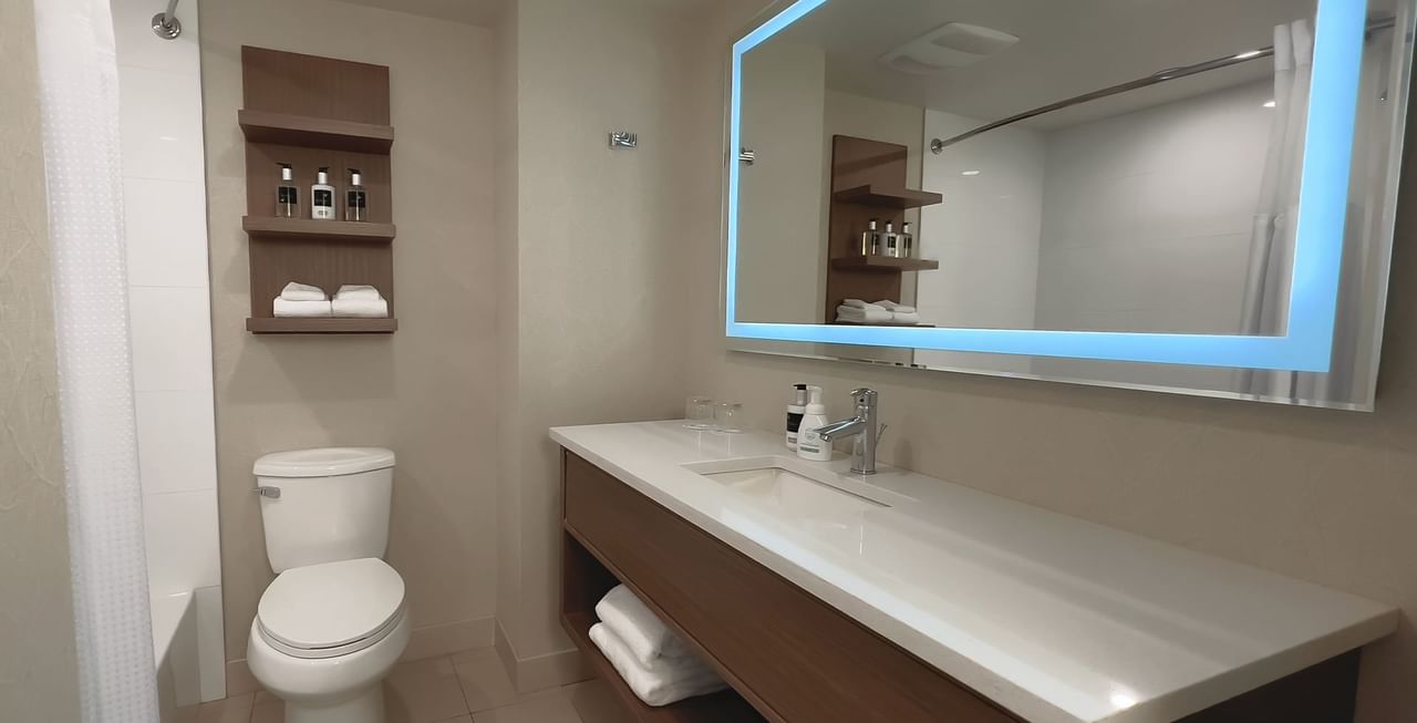 Hotel bathroom with mirror, soap, towels, toilet, and sink