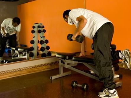 Man lifting weights in the Off Site Fitness Center at Pensativo House Hotel