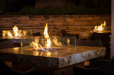 Outdoor dining area in Cascades restaurant with multiple fire pits on stone tables at The Stanley Hotel