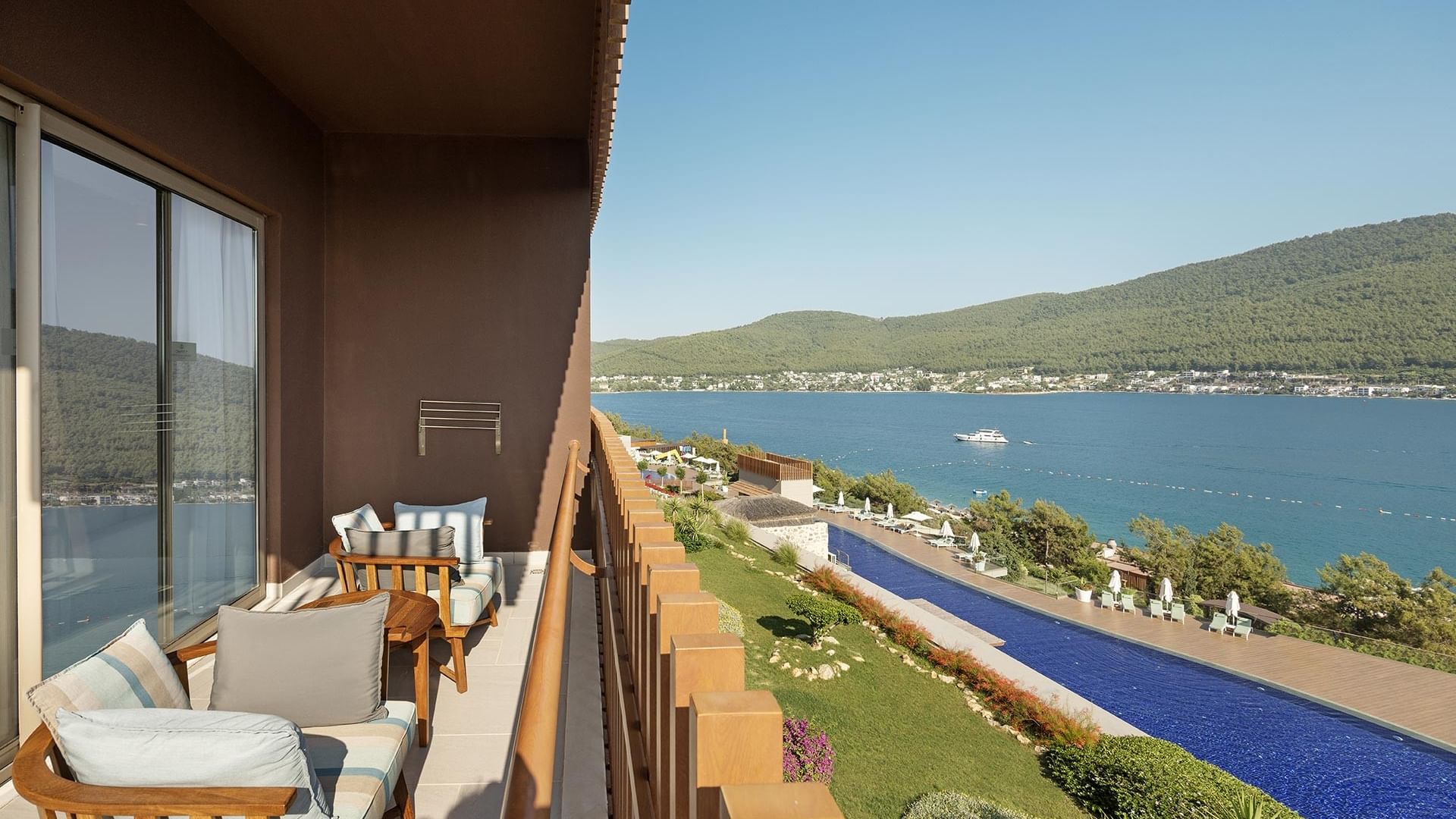 Балкон стандартного номера с видом на море в отеле Titanic Luxury Collection Bodrum: оснащён диванами, большими окнами и открывает вид на бассейн и море.