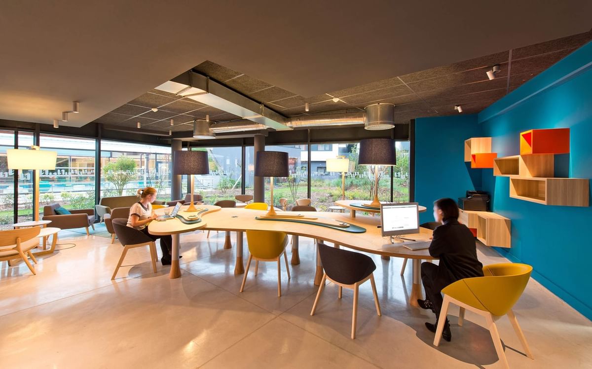 Business Corner arranged with a long table and chairs at Nomad Hotels Paris Roissy