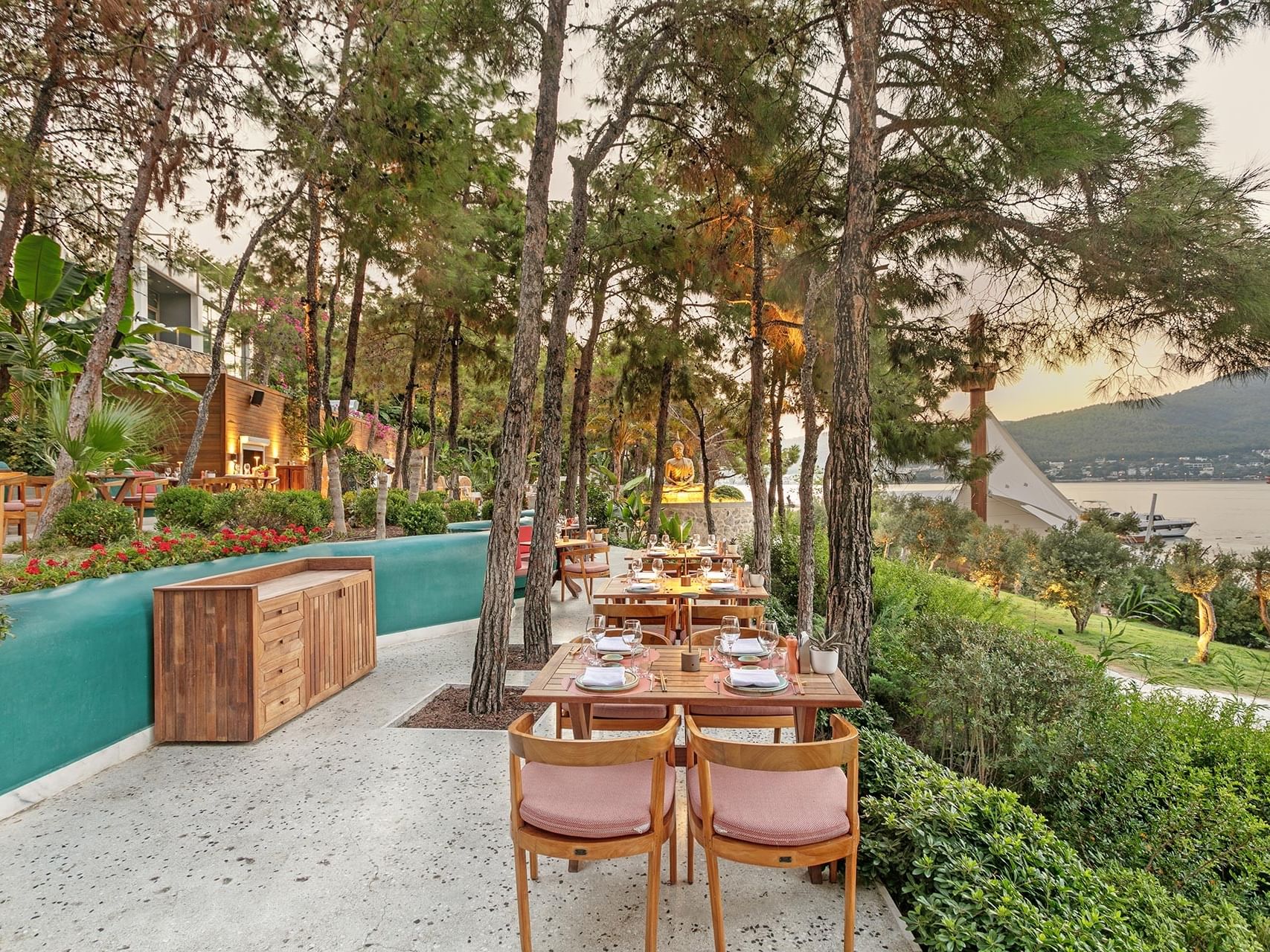 Outdoor restaurant area at Titanic Luxury Collection Bodrum, surrounded by trees.