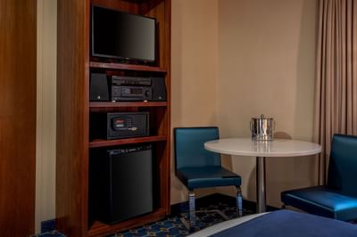 Television on a wooden shelf unit near a table with two chairs in Queen Atrium View at Harborside Inn Boston