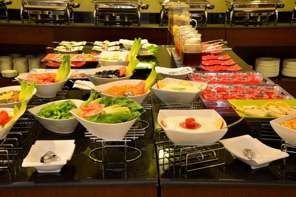 Buffet spread featuring fruit and salad in bowls by food warmers served in Naviti Restaurant at Naviti By Warwick Dammam