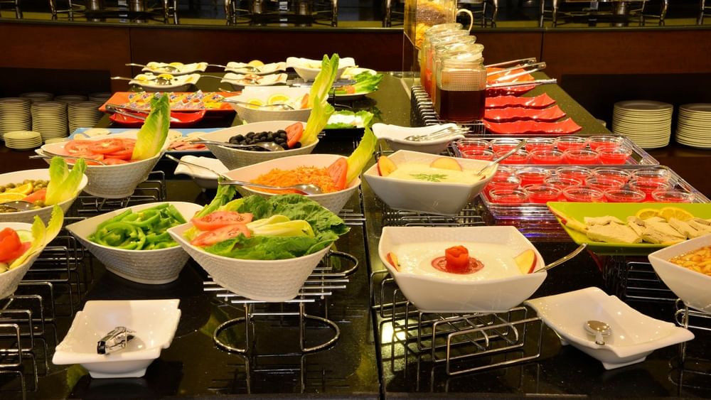 Buffet spread featuring fruit and salad in bowls by food warmers served in Naviti Restaurant at Naviti By Warwick Dammam